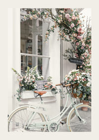 Zdjęcie białego roweru z koszem kwiatów przed fasadą ozdobioną kwiatami-3