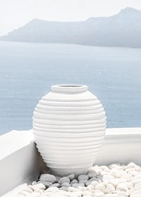 Photograph of white ceramic vase against sea and mountains on Santorini-7