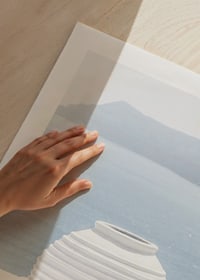 Photograph of white ceramic vase against sea and mountains on Santorini-9