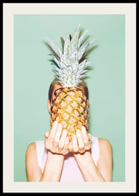 Foto einer Frau, die vor einem hellgrünen Hintergrund eine Ananas vor ihr Gesicht hält-2