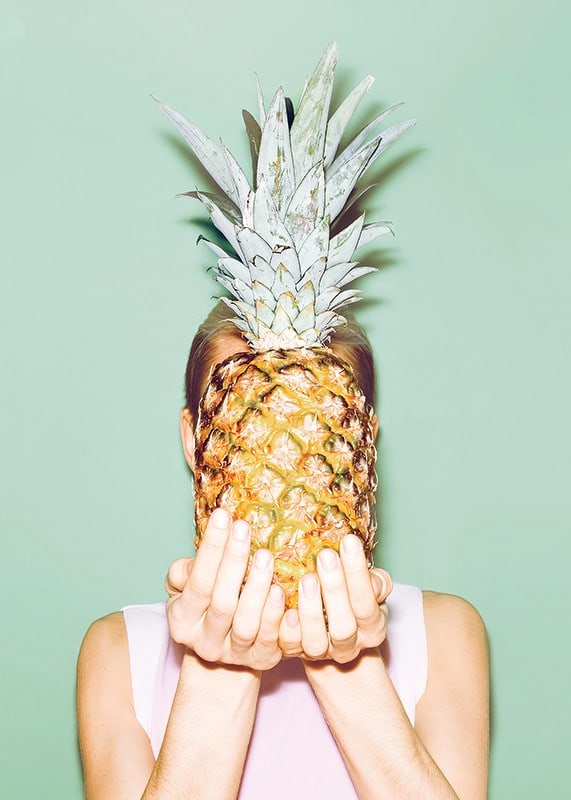 Fotografi av kvinna som håller en ananas framför ansiktet mot ljusgrön bakgrund-12