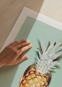 Fotografi av kvinna som håller en ananas framför ansiktet mot ljusgrön bakgrund-9