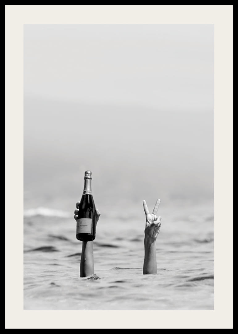 Svartvitt fotografi med två armar i vatten, en håller champagne-12