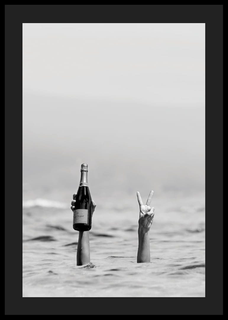 Svartvitt fotografi med två armar i vatten, en håller champagne-12