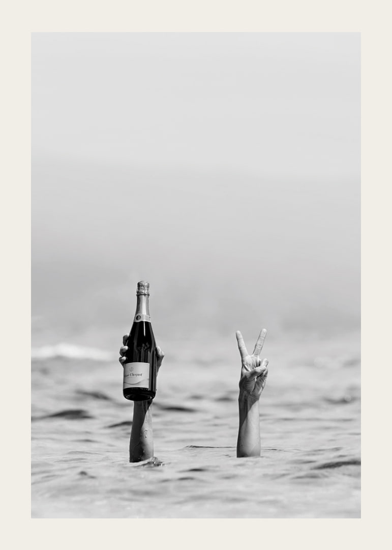 Fotografia in bianco e nero di due braccia nell'acqua, una delle quali tiene in mano dello champagne-12