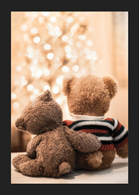 Two teddy bears from behind against bright Christmas tree, soft colors-5