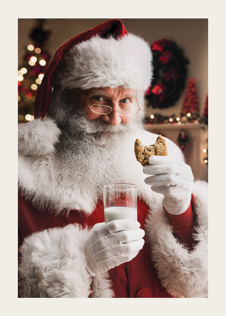 Jultomte med glas mjölk och chokladkaka i julmiljö-12