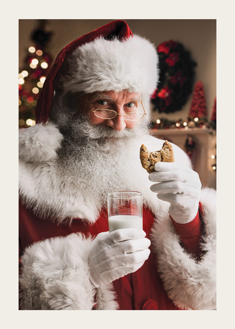 Święty Mikołaj ze szklanką mleka i czekoladowym ciastem w świątecznej scenerii-12