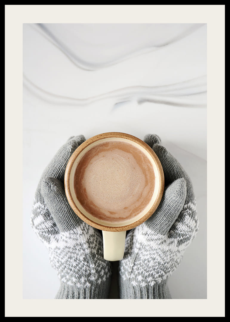 Gråstickade vantar håller kopp med varm choklad, ovanifrån-12