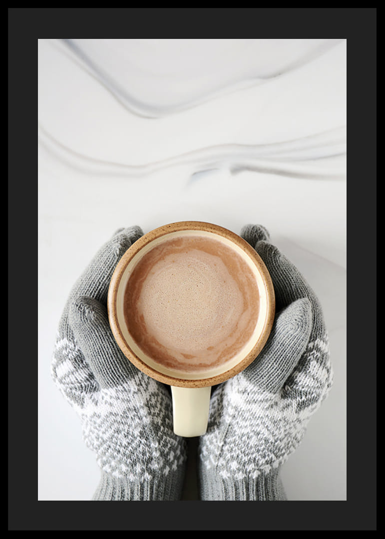 Gråstickade vantar håller kopp med varm choklad, ovanifrån-12