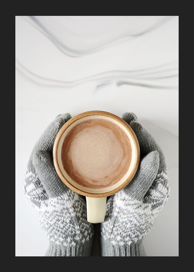 Gråstickade vantar håller kopp med varm choklad, ovanifrån-12