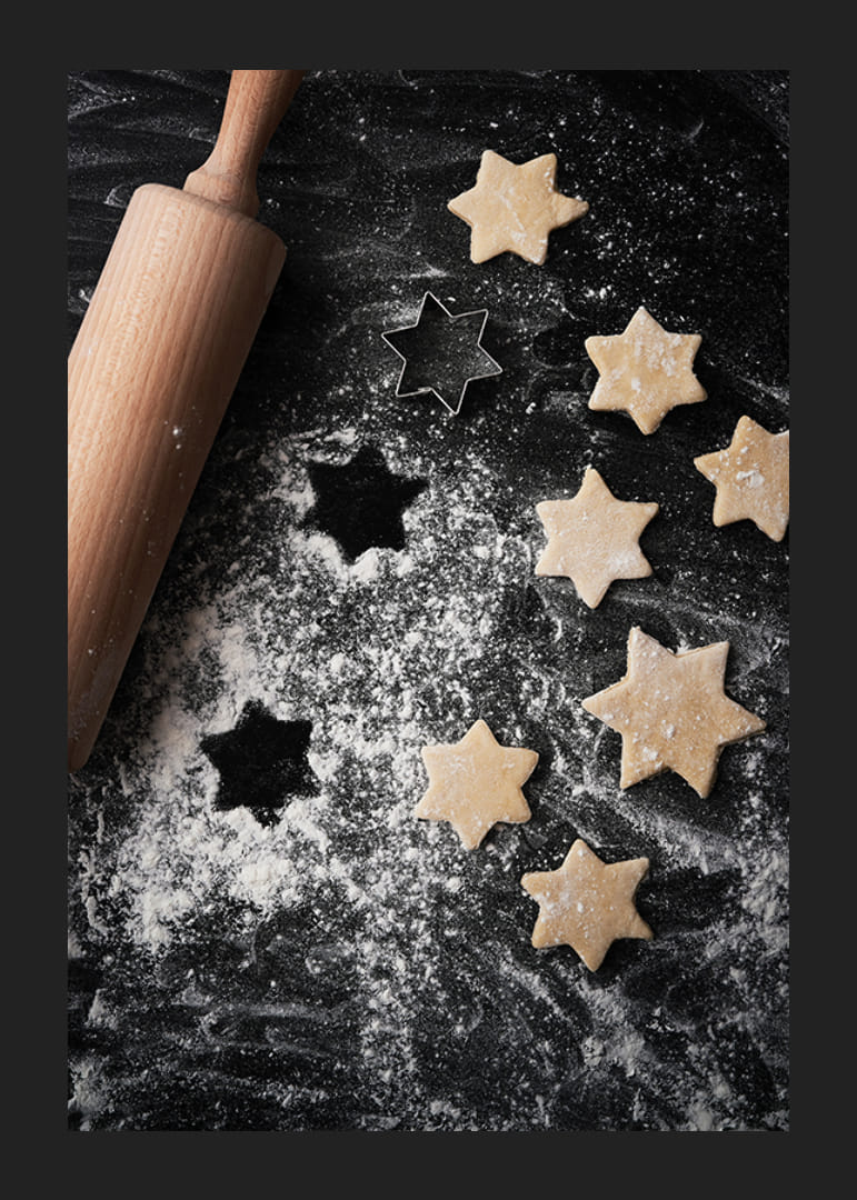Fotografia rozvaľkaného cesta, valčeka a vykrajovačky na sušienky v tvare hviezdy na pomúčenom stole-12