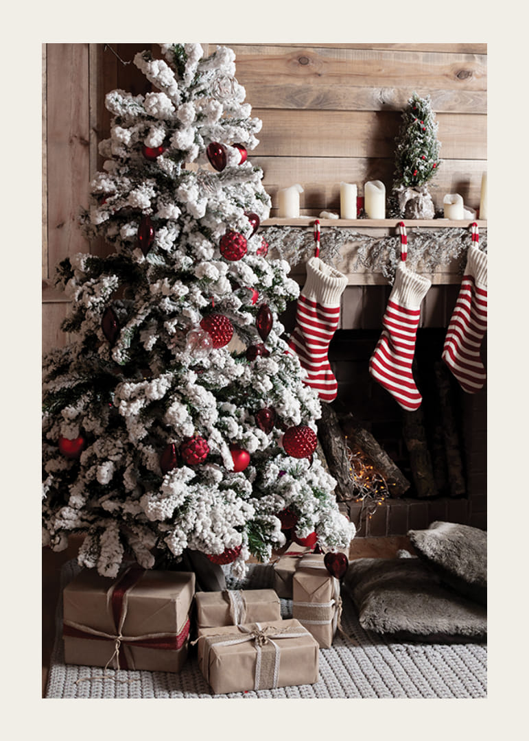 Zasnežená jedľa s červenými guľami, vianočnými darčekmi a pruhovanými ponožkami-12