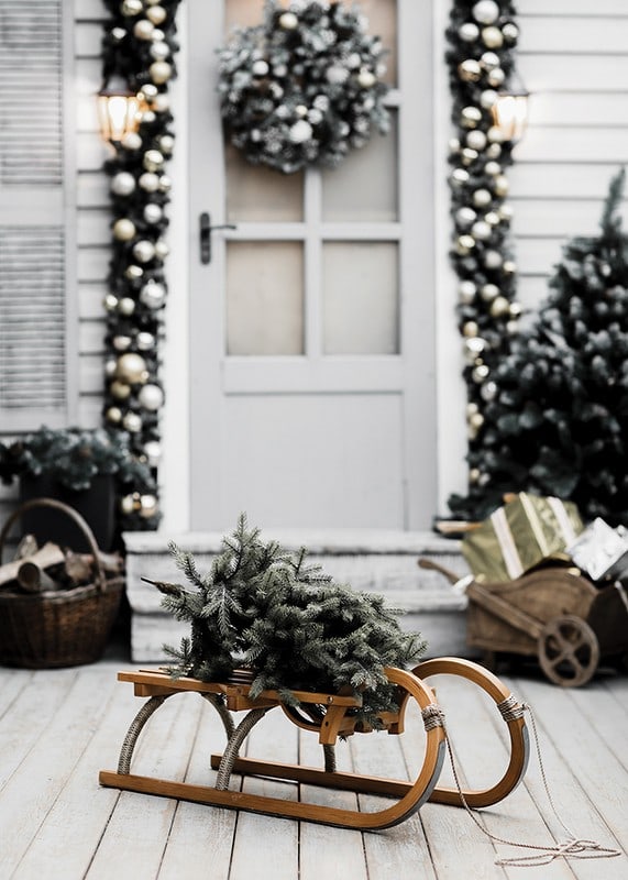 Photograph of fir tree on wooden sled in front of decorated door-12