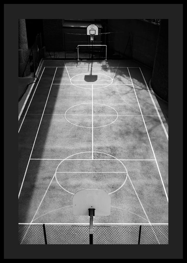 Black and white photo of empty basketball court with sharp lines and shadows-12