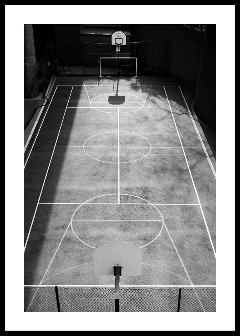 Black and white photo of empty basketball court with sharp lines and shadows-12