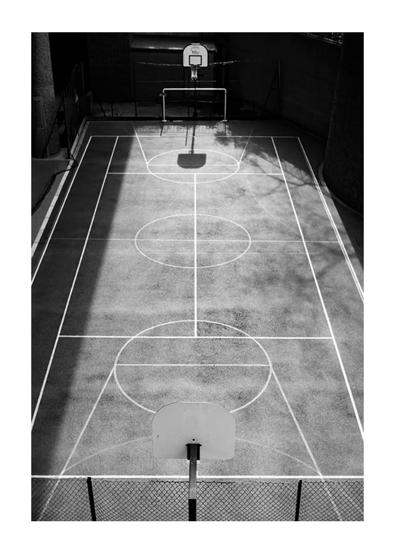 Black and white photo of empty basketball court with sharp lines and shadows-12