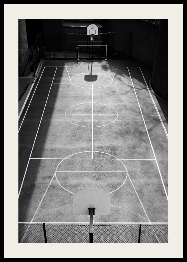 Black and white photo of empty basketball court with sharp lines and shadows-12