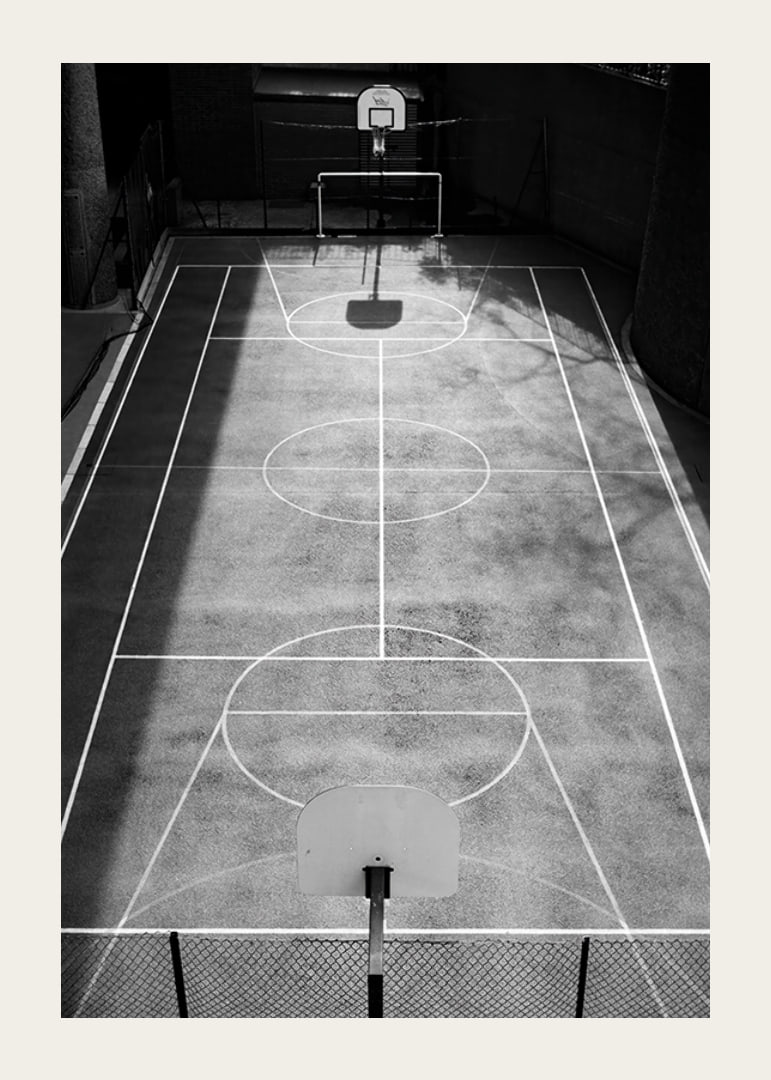 Black and white photo of empty basketball court with sharp lines and shadows-12