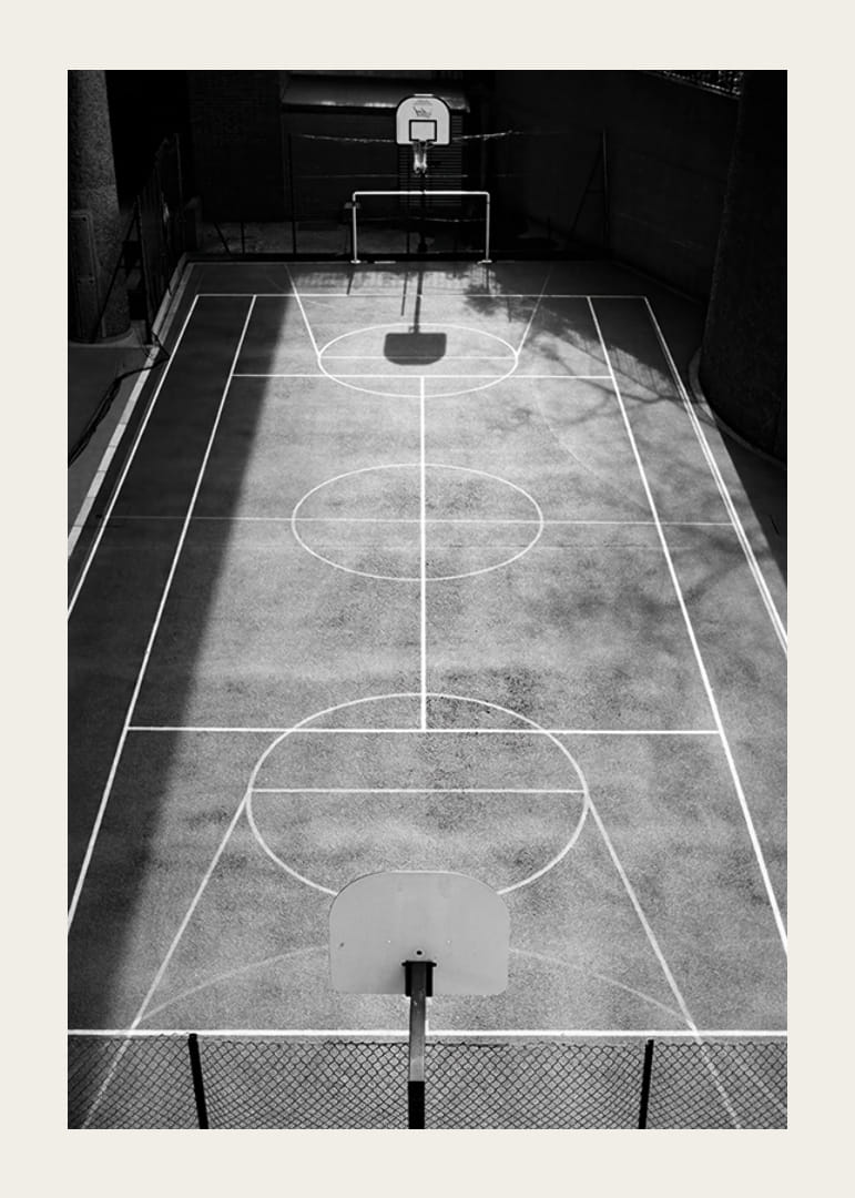 Black and white photo of empty basketball court with sharp lines and shadows-12