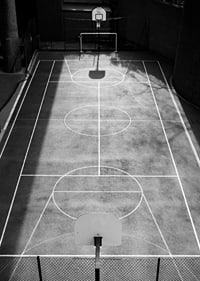 Black and white photo of empty basketball court with sharp lines and shadows-7