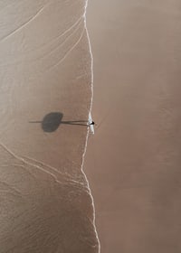 Flygbild av ensam surfare med bräda på sandstrand-7