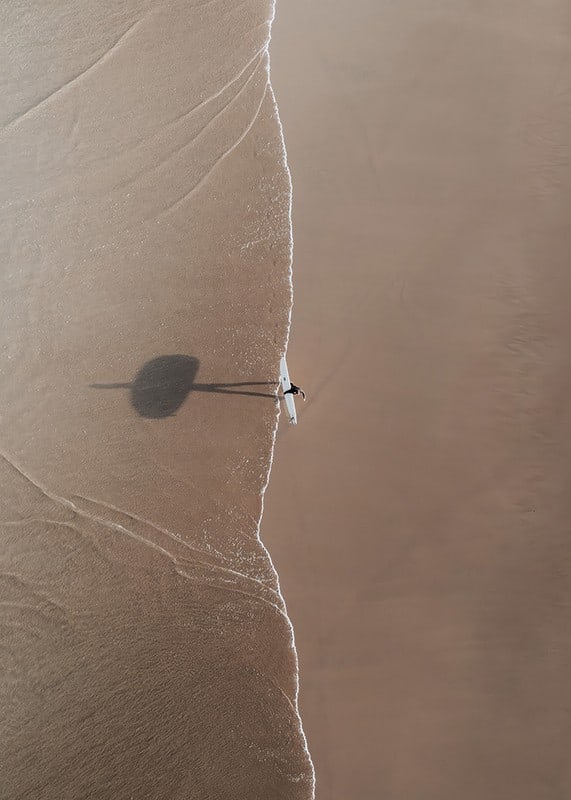 Flygbild av ensam surfare med bräda på sandstrand-12
