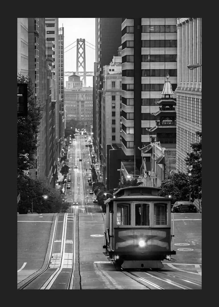 Svartvit stadsvy med spårvagn i San Francisco och bro i bakgrunden-12