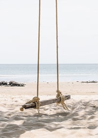 Fotografia di un'altalena di legno su una spiaggia di sabbia chiara in riva al mare-7