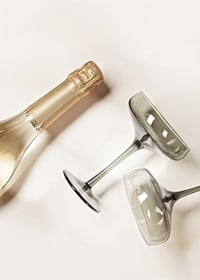 Champagnerflasche und zwei Gläser vor hellem Hintergrund, fotografisch-7