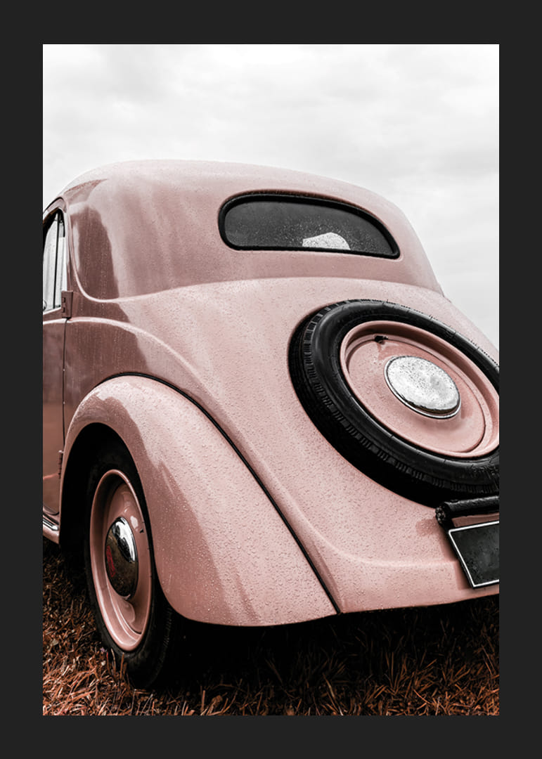 Photograph of classic pink vintage car in grass, rear view-12