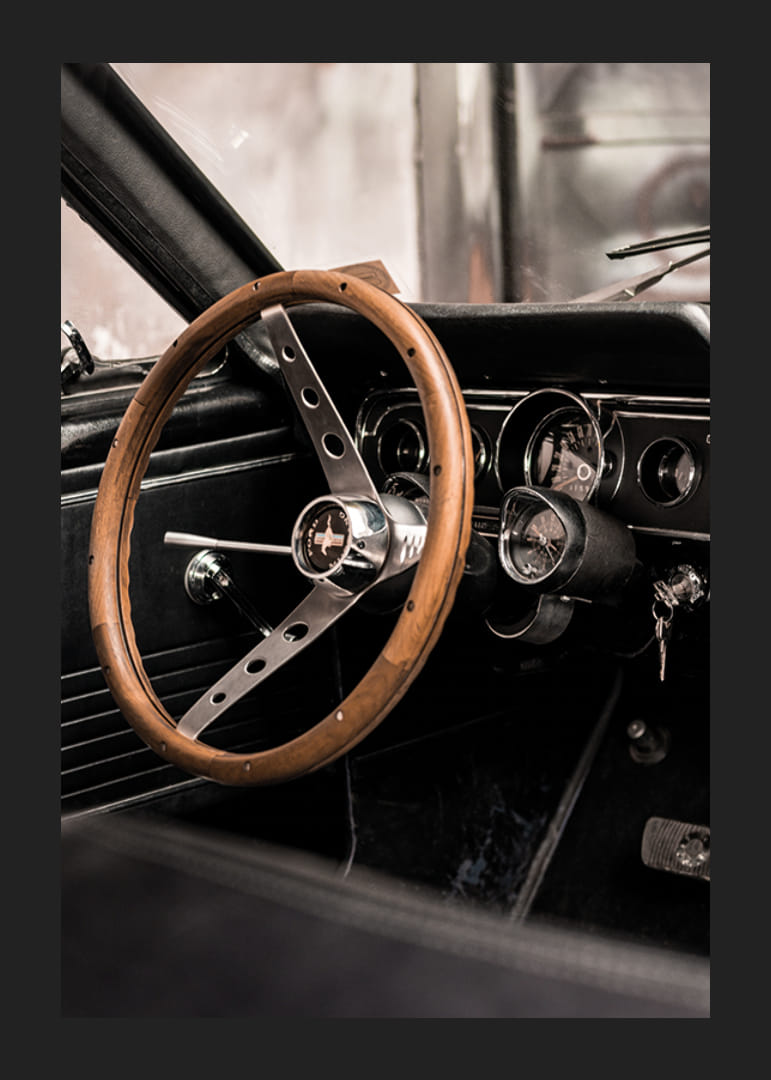 Fotografía del interior de un coche clásico con un volante de madera enfocado.-12