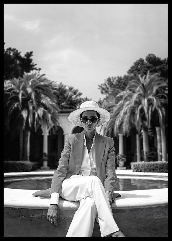 Black and white photo of woman in suit and sun hat by pool-12