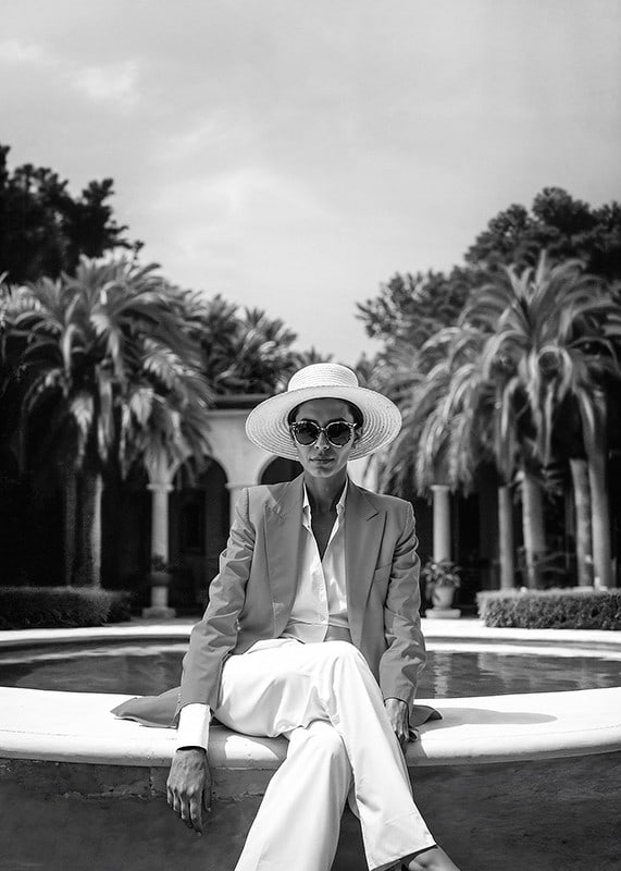 Black and white photo of woman in suit and sun hat by pool-12