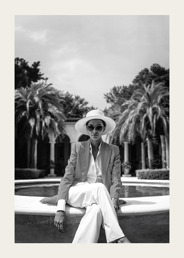 Black and white photo of woman in suit and sun hat by pool-12