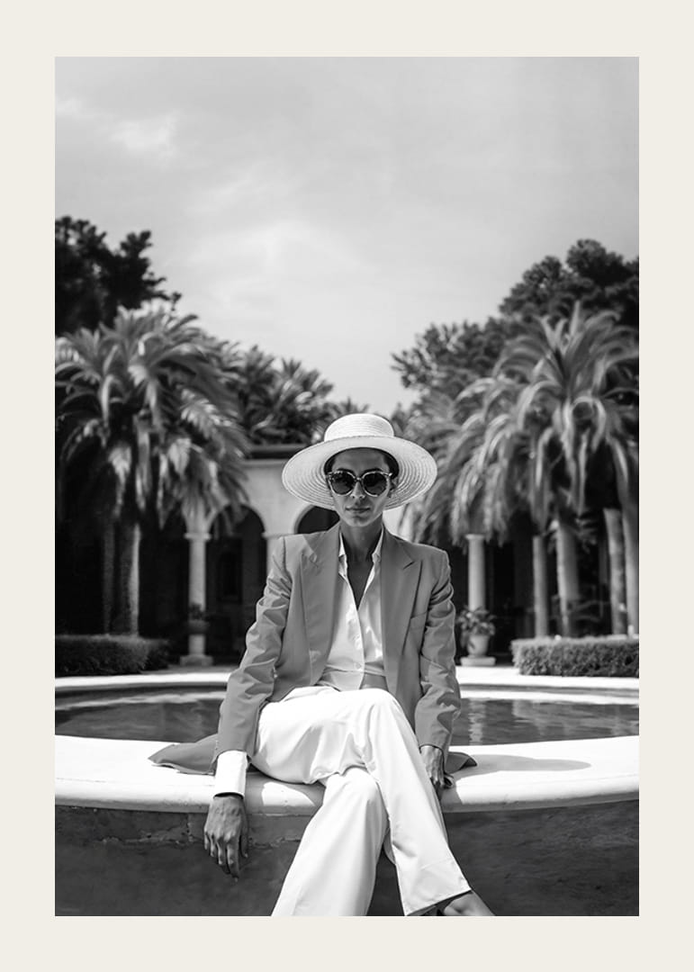 Black and white photo of woman in suit and sun hat by pool-12