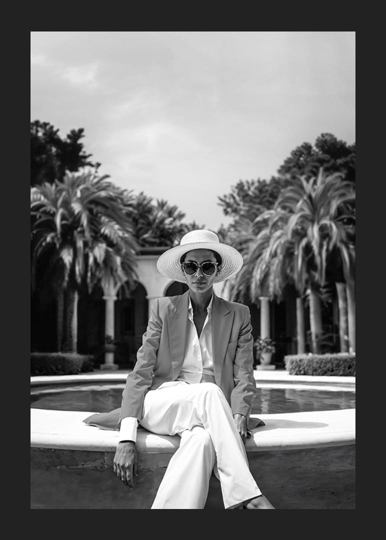 Black and white photo of woman in suit and sun hat by pool-12