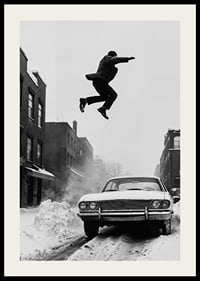Black and white city scene with man jumping over snow-covered car-2