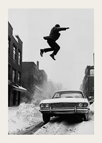 Black and white city scene with man jumping over snow-covered car-3