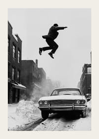 Schwarz-weiße Stadtszene mit Mann, der über ein schneebedecktes Auto springt-3