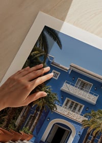 Photograph of blue villa with palm trees and long swimming pool in the foreground-9
