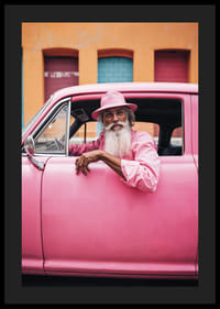 Äldre man med långt skägg i rosa bil framför färgglad fasad-4