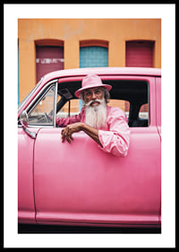 Elderly man with long beard in pink car in front of colorful facade-0