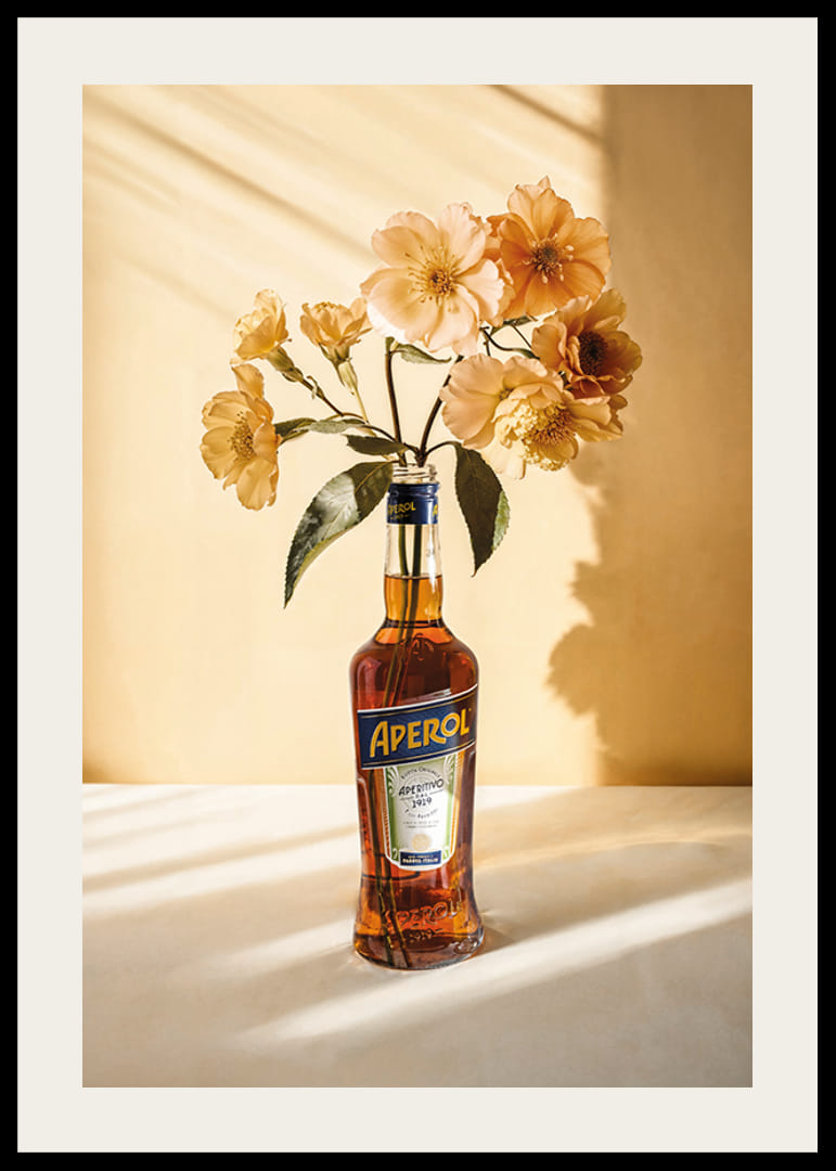 Fotografia della bottiglia di Aperol con fiori gialli brillanti in una luce soleggiata-12