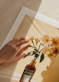 Fotografi av Aperolflaska med ljusgula blommor i soligt ljus-9