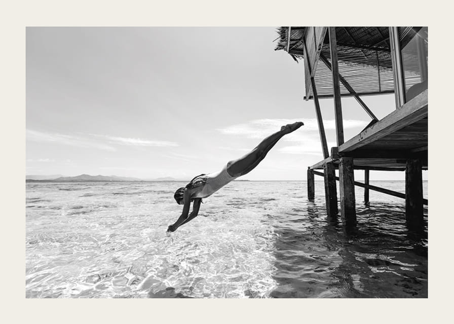 Svartvit poster med ett fotografi på en kvinna som dyker från en träbrygga-12