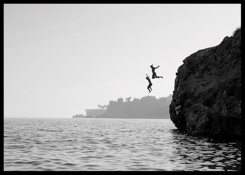 Afiș alb-negru cu o fotografie a doi oameni sărind de pe o stâncă în mare-12