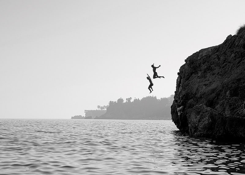 Black and white poster with a photograph of two people jumping from a cliff into the sea-12