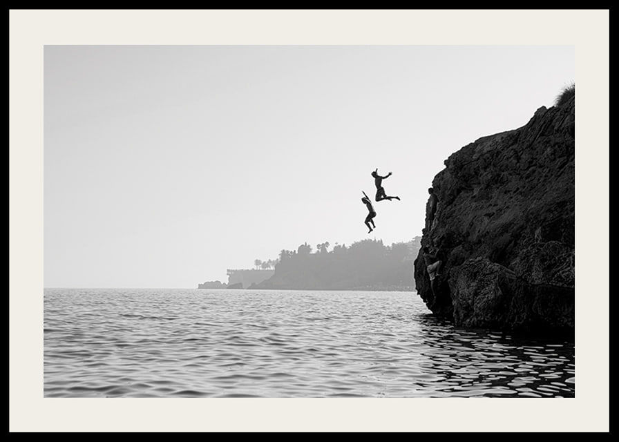 Black and white poster with a photograph of two people jumping from a cliff into the sea-12