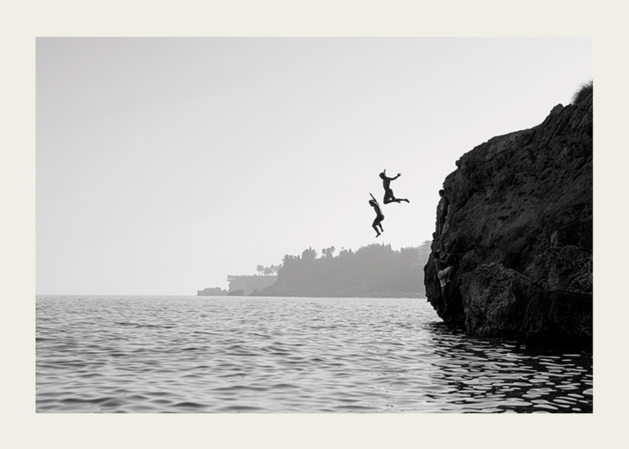 Black and white poster with a photograph of two people jumping from a cliff into the sea-12